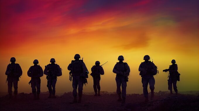 Silhouette Of Veterans Walking In A Group Towards An Orange And Red Sky.